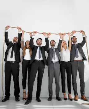 People holding rope together indoors. Unity concept