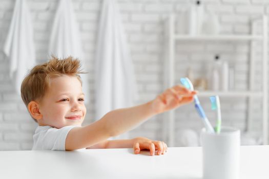 Cute Little boy reaching out for toothbrush in bathroom