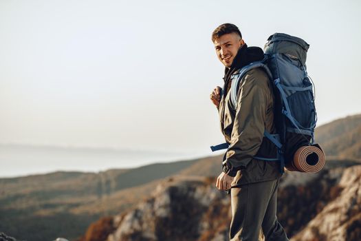 Young caucasian man traveler with big backpack hiking in the mountains alone