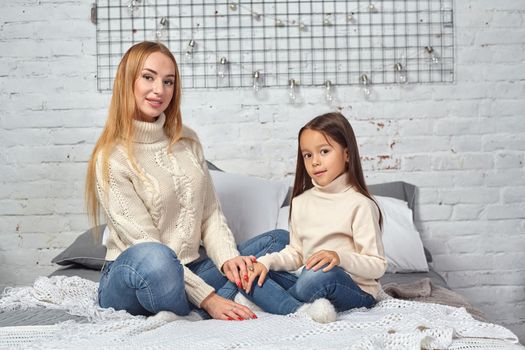 Happy loving family. Mother and her daughter child girl playing and hugging on bed