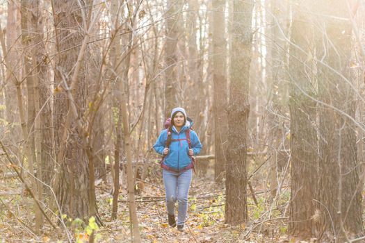 adventure, travel, tourism, hike and people concept - smiling woman walking with backpacks over autumn natural background.