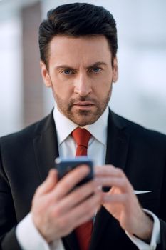 close up.businessman is typing SMS on a smartphone.people and technology