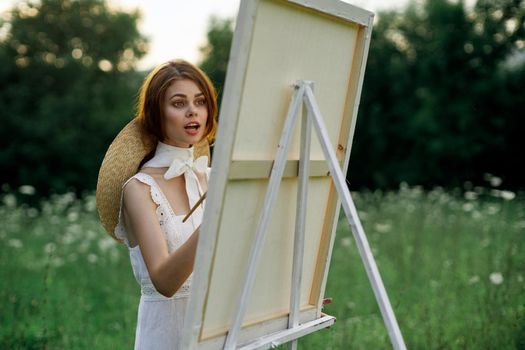 Woman in white dress paints a picture outdoors hobby creative. High quality photo