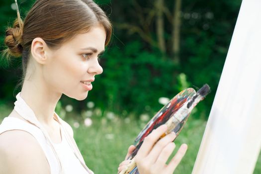 woman artist paints palette easel nature drawing. High quality photo