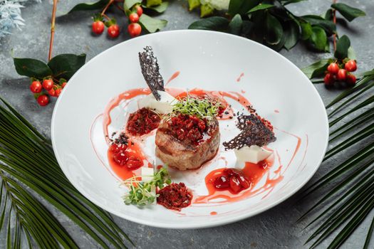 Appetizing beef in sweet sauce close up. Chopped beef meat in cherry sauce with vegetables on plate. Delicious european cuisine.