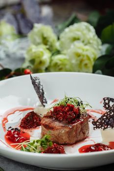 Appetizing beef in sweet sauce close up. Chopped beef meat in cherry sauce with vegetables on plate. Delicious european cuisine.