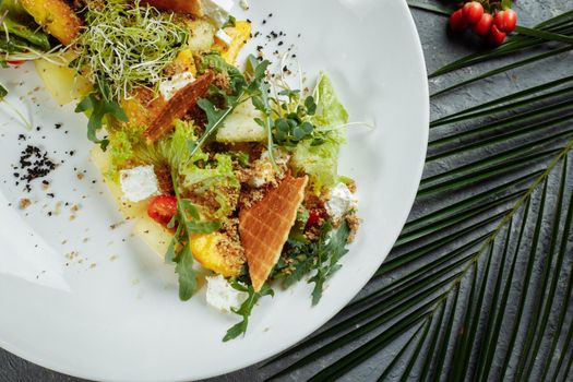 Summer diet salad with leaves of lettuce, watermelon, peach and feta cheese. On a light blue background copy space.