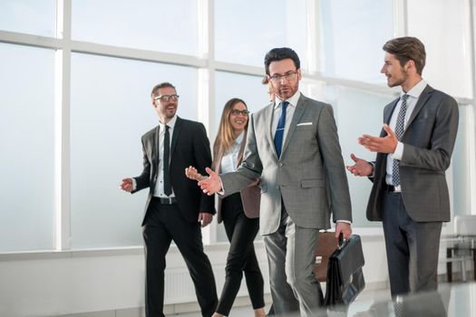 business people group standing together as team by window in modern bright office interior