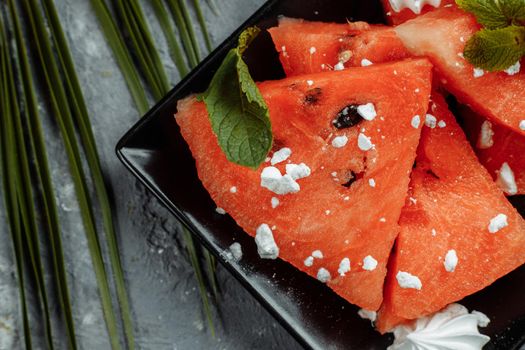 Pieces of fresh red watermelon on a black plate.