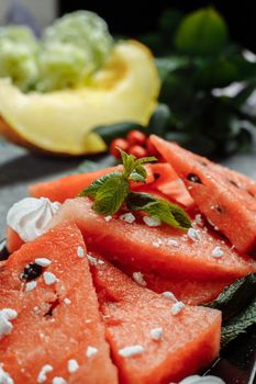 Pieces of fresh red watermelon on a black plate.