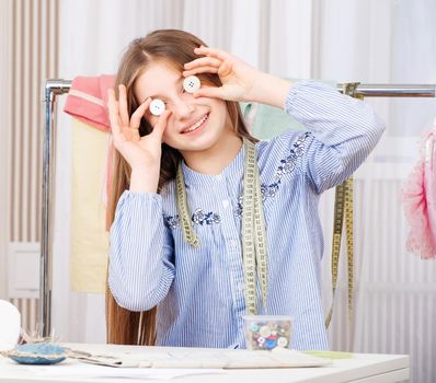 Adorable seamstress girl with different plastic buttons