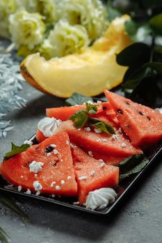 Pieces of fresh red watermelon on a black plate.