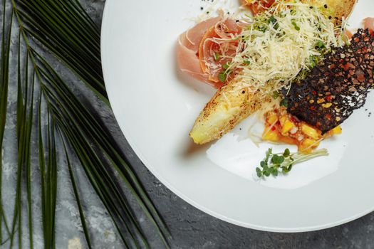 baked melon with parmesan and jamon on a white plate.