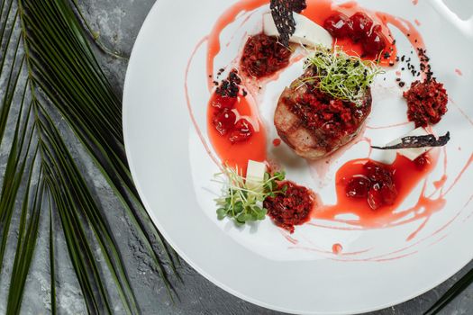 Appetizing beef in sweet sauce close up. Chopped beef meat in cherry sauce with vegetables on plate. Delicious european cuisine.