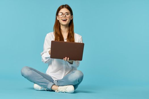 woman with laptop learning internet online education blue background. High quality photo