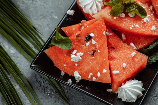 Pieces of fresh red watermelon on a black plate.