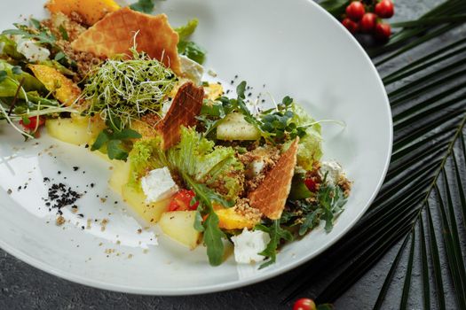 Summer diet salad with leaves of lettuce, watermelon, peach and feta cheese. On a light blue background copy space.