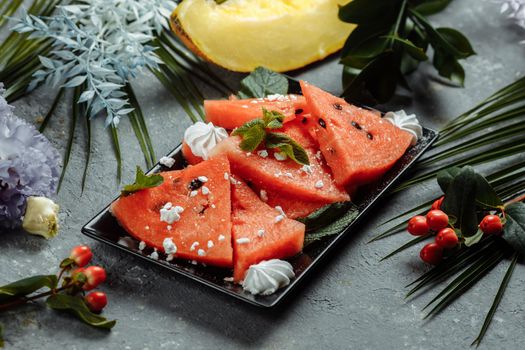 Pieces of fresh red watermelon on a black plate.