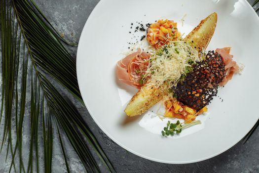 baked melon with parmesan and jamon on a white plate.