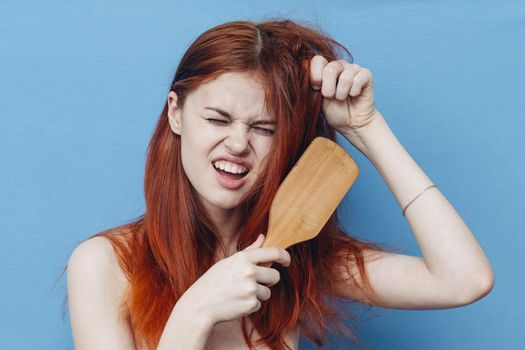 pretty woman combing naughty hair blue background. High quality photo