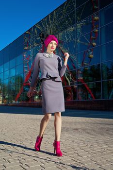 Fashion photo of a beautiful woman in front of a building with reflection of Ferris wheel at summer time