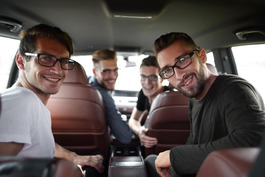 Handsome young man with friends in blue shirt driving car