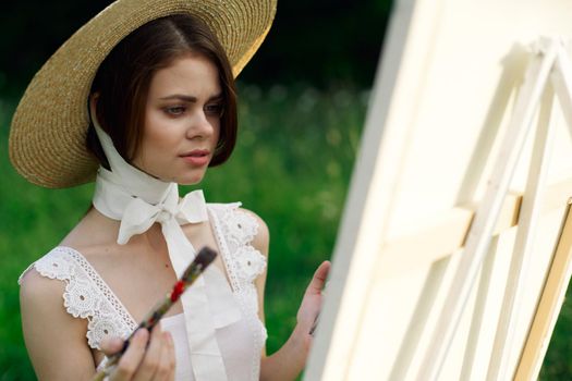 woman artist in hat with brush paints a picture. High quality photo