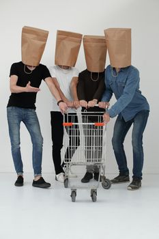 men with paper bags on head and shopping cart in hands on isolated background