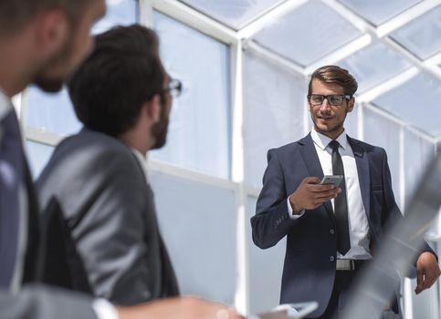 businessman with a smartphone standing in his ofiice.people and technology