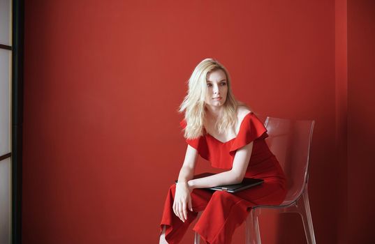 Young adult woman sitting on a chair and holding laptop