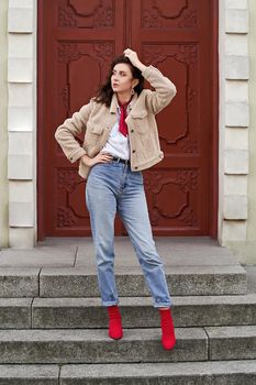 Young beautiful woman in red knitted fabric block heel sock shoes, blue denim jeans pants and teddy jacket coat