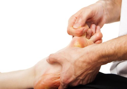 Closeup of foot receiving massage on white