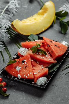 Pieces of fresh red watermelon on a black plate.