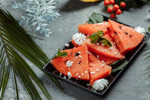 Pieces of fresh red watermelon on a black plate.