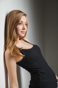 Beautiful young woman wearing jeans and black t-shirt over gray background