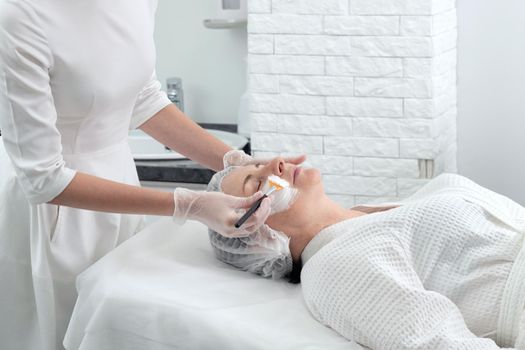 Mature woman receiving wwhte facial mask in spa beauty salon