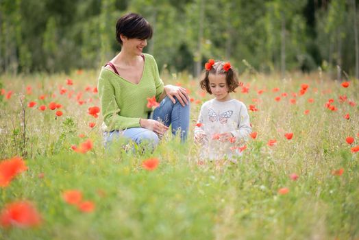 Happy mother with her little daughter in poppy field