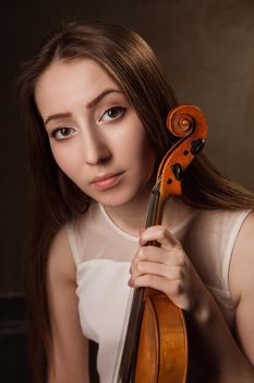 Beautiful young woman playing violin over black background