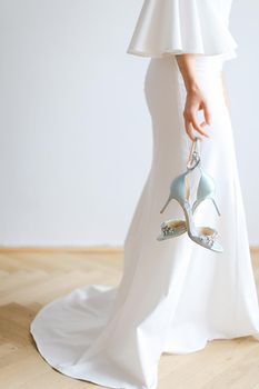 Closeup bride keeping dress and shoes. oncept of wedding day.