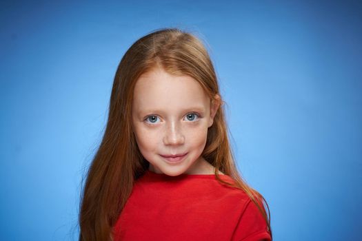 cheerful cute red-haired girl childhood blue background. High quality photo
