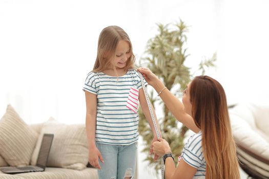 attentive mother and daughter make measurements for new clothes .the concept of parenting