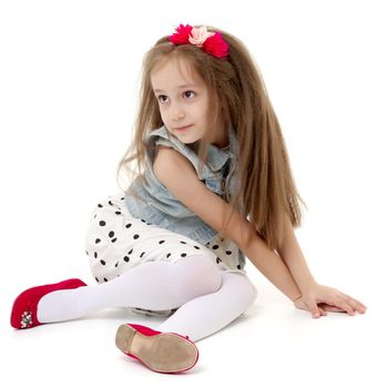 Little girl is sitting on the floor. The concept of a happy childhood. Isolated on white background.