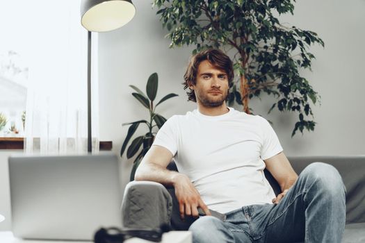 Relaxed casual man sitting on the sofa and looking at camera, man portrait
