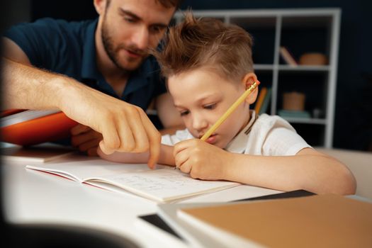 Father helping his little son with school homework close up