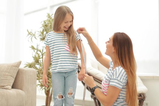 attentive mother and daughter make measurements for new clothes .the concept of parenting