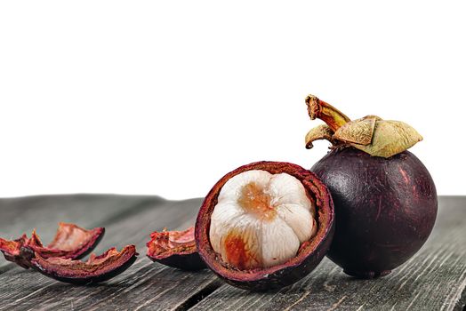 Whole and opened mangosteen with shells on table isolated on white background