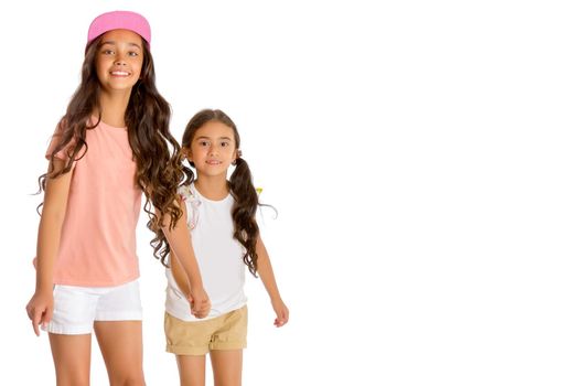 Two beautiful little Asian girls skate on roller skates. The concept of advertising sports goods, a healthy lifestyle, a happy childhood. Isolated on white background.