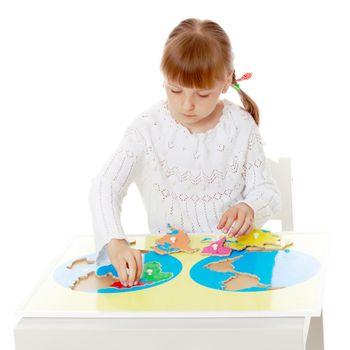 A little girl in Montessori kindergarten sits at a table and studies Montessori stuff. The concept of school and preschool education, harmonious development of the child. Isolated on white background.