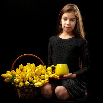 Beautiful little girl with a bouquet of tulips, studio photo on a black background. The concept of happy people, childhood.