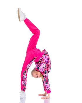 A girl gymnast performs an acrobatic element on the floor. The concept of childhood, sport, healthy lifestyle. Isolated on white background.